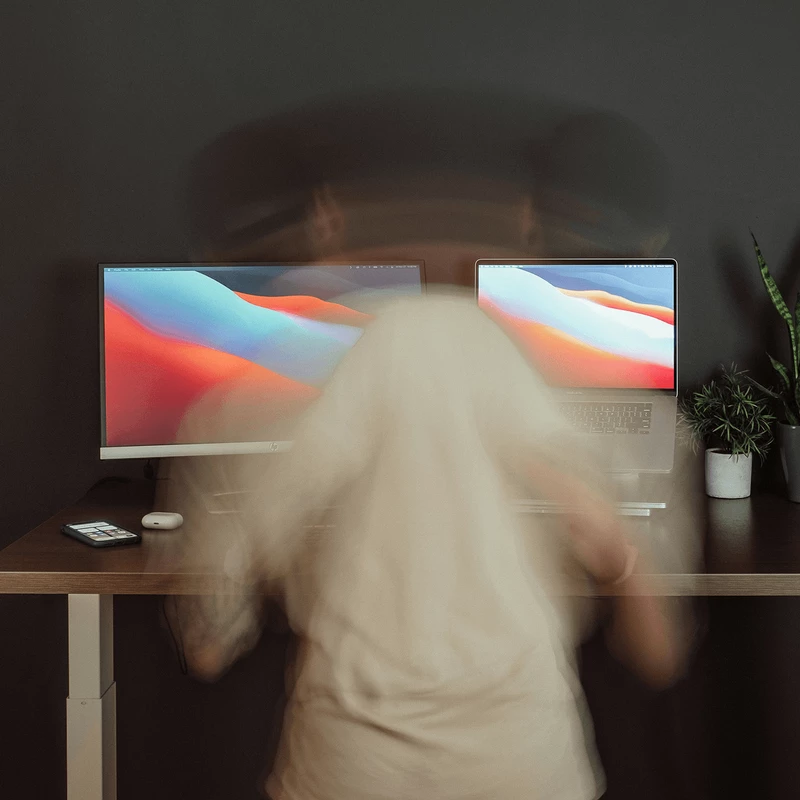 Photo d'une personne de dos, face à son poste de travail