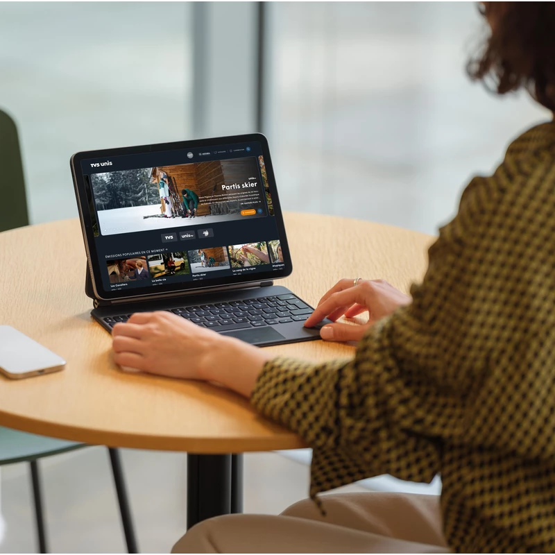 Une personne assise dans un café utilise l'application de TV5 sur iPad