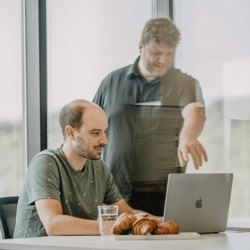 Two team members working together in front of a computer