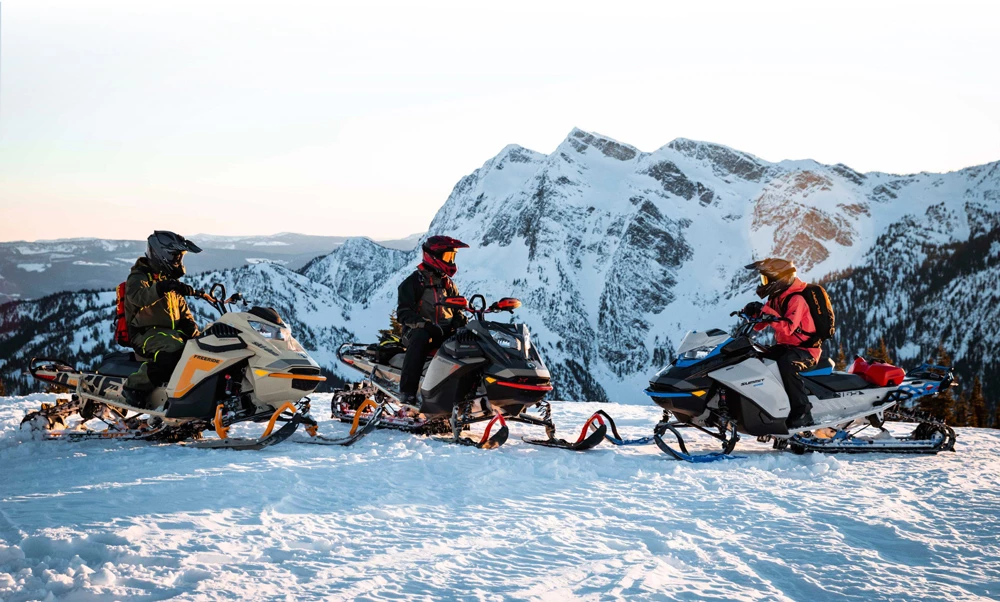 Groupe de motoneigistes devant des montagnes